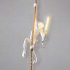 White monkey on a natural rope with a long filament bulb held in one hand, on a smooth grey backdrop; this Clérachic pendant.