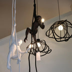 Black and white monkey lights shown together in a loft-style room beside dark wire globe pendants, each with a lit bulb; Clérachic.