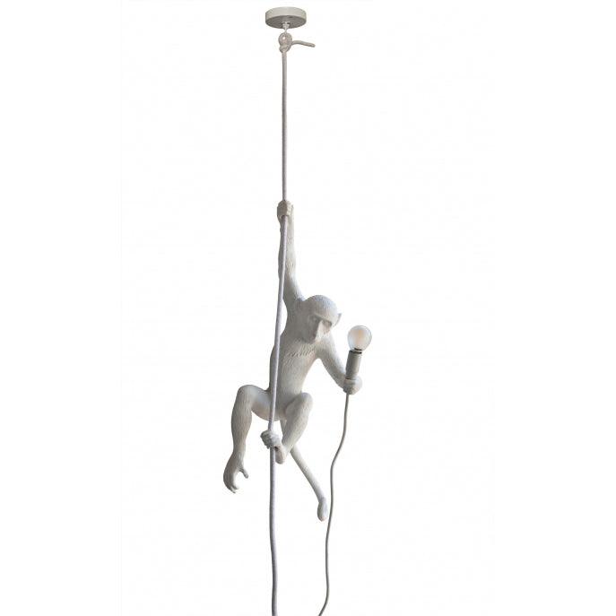 Full-length view of a white monkey pendant from its round ceiling canopy down a thin rope to the figure and its bulb; from Clérachic.