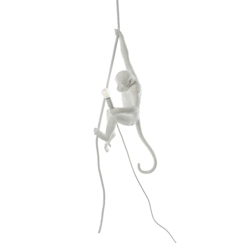 Small white monkey gripping a thin rope with one hand, bulb holder in the other, shown on a white background; this Clérachic pendant.