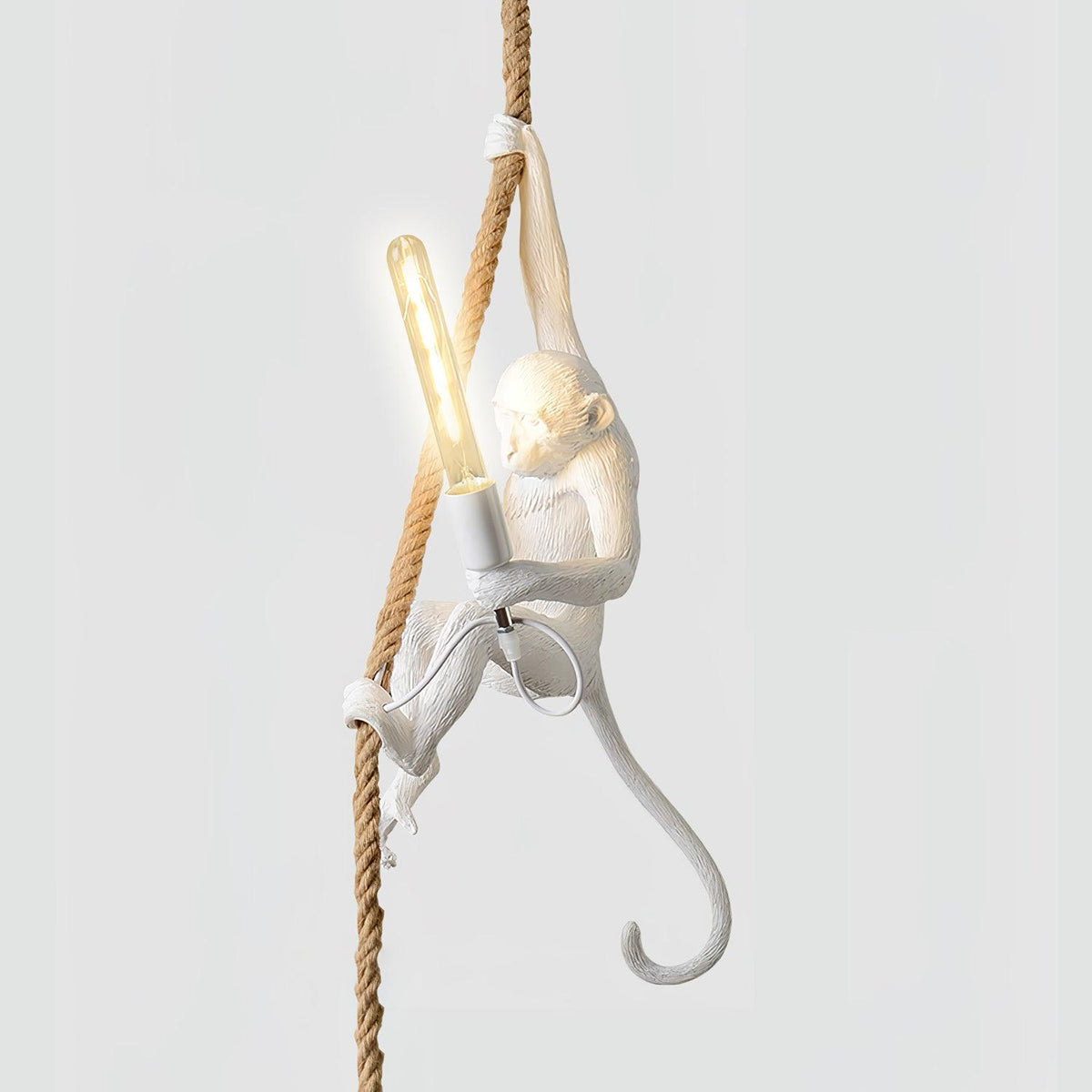 White monkey with one arm stretched up the rope and a long filament bulb lit in its hand, on a pale background; this Clérachic pendant.