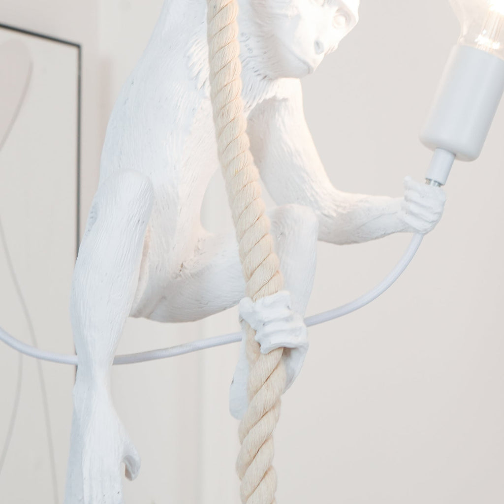 Detail of the monkey's body, its arm gripping the rope and the cable looping to the bulb holder, on this Clérachic pendant.