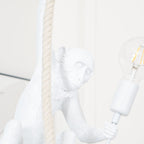 Close view of the monkey's face and the large clear filament bulb in its hand, with the rope at left; this Clérachic pendant.