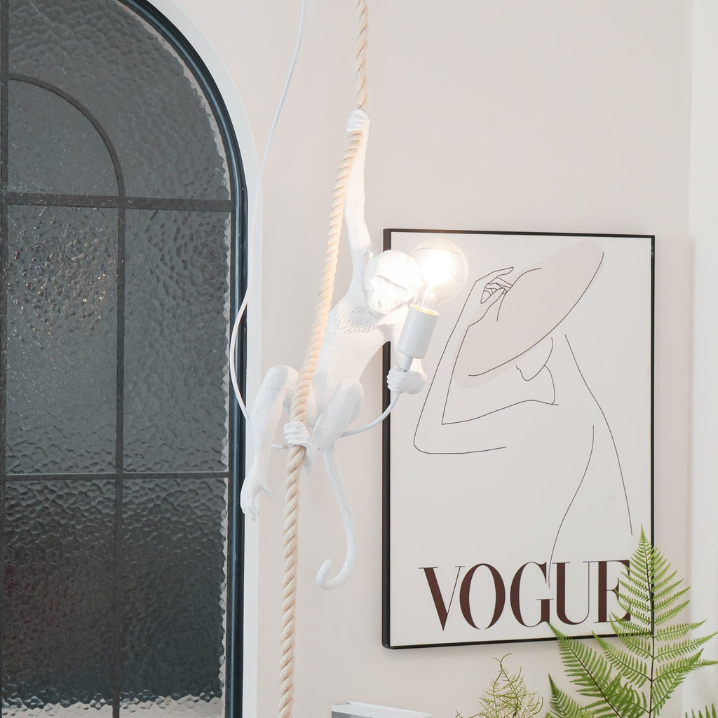 White monkey and its glowing round bulb in front of an arched window and a large framed print, with a fern at the bottom; from Clérachic.