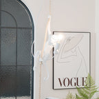 White monkey and its glowing round bulb in front of an arched window and a large framed print, with a fern at the bottom; from Clérachic.