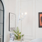 This Clérachic pendant hangs with its white monkey lit beside a leopard print, with a framed print, a fern and books below.