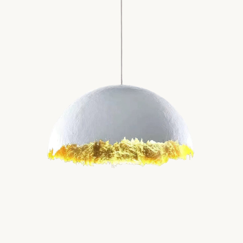 Clérachic pendant with a pale domed shade and a jagged, gold-leaf lower edge, hung on a thin cord against a white backdrop.