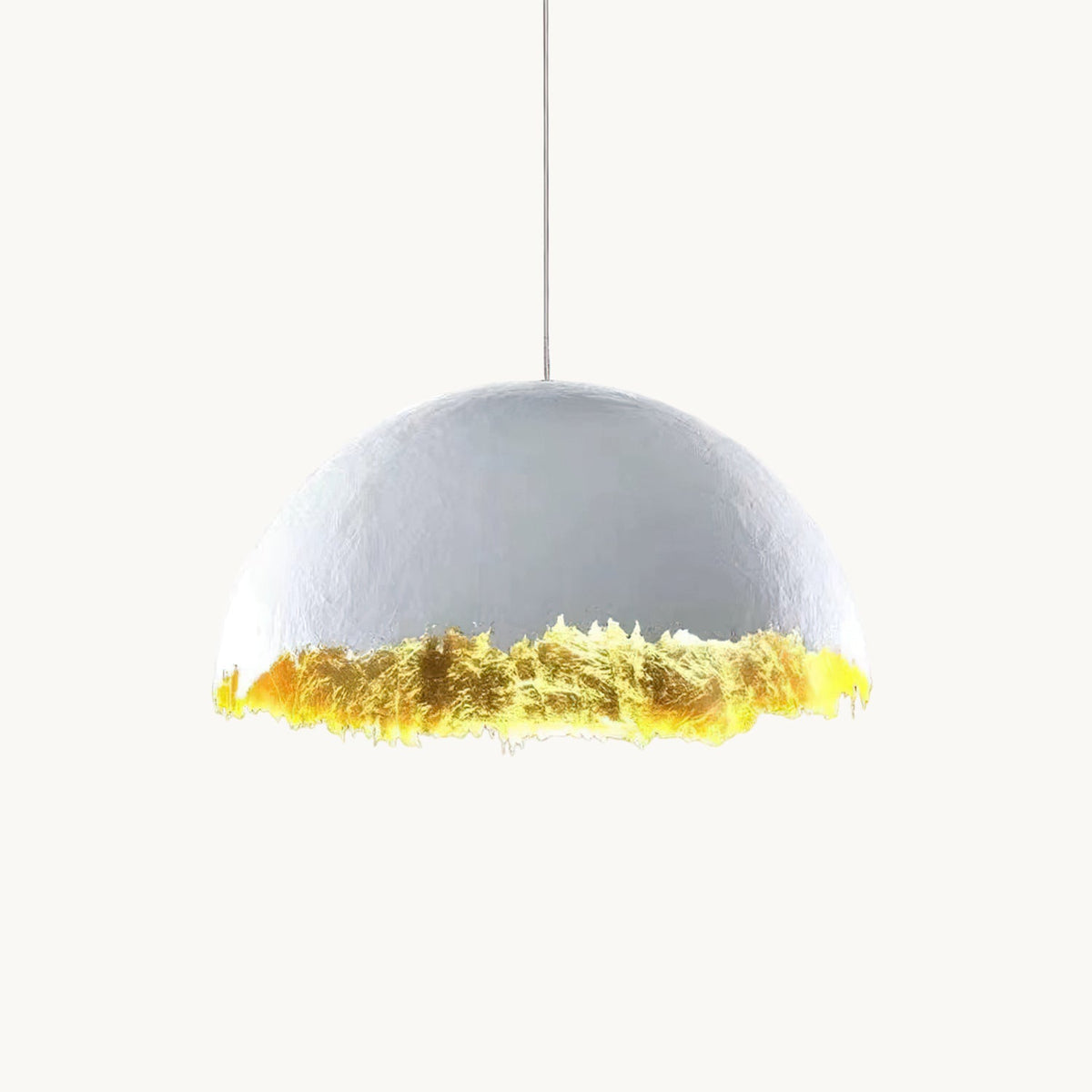 Clérachic pendant with a pale domed shade and a jagged, gold-leaf lower edge, hung on a thin cord against a white backdrop.
