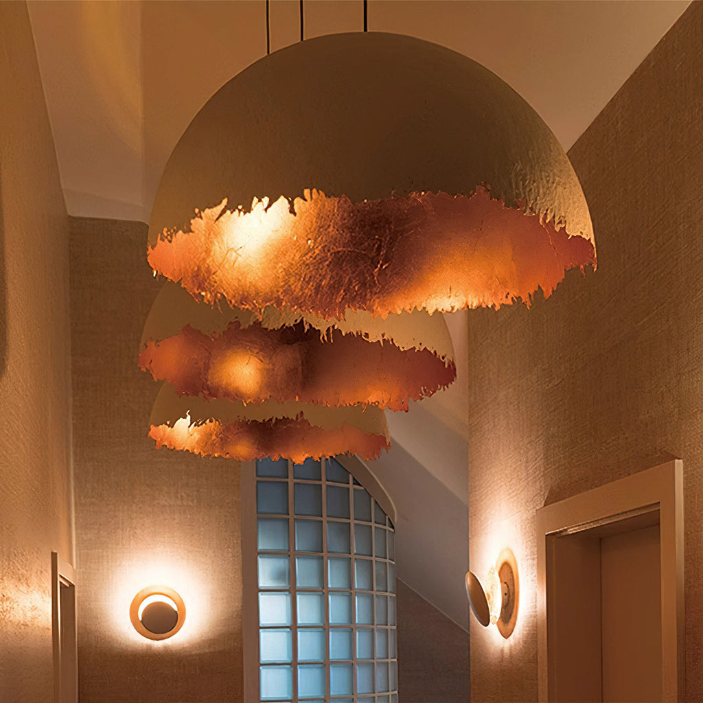 Three stacked Clérachic dome pendants hang at different heights, lit from inside in a deep copper-toned colour, in a narrow hall.