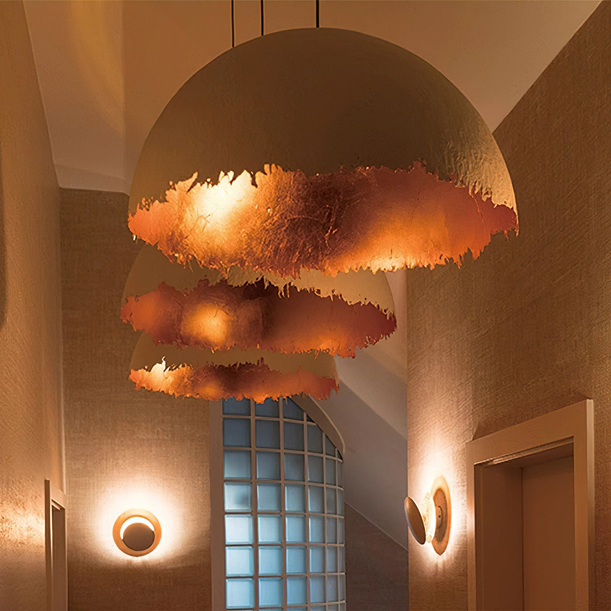 Three stacked Clérachic dome pendants hang at different heights, lit from inside in a deep copper-toned colour, in a narrow hall.