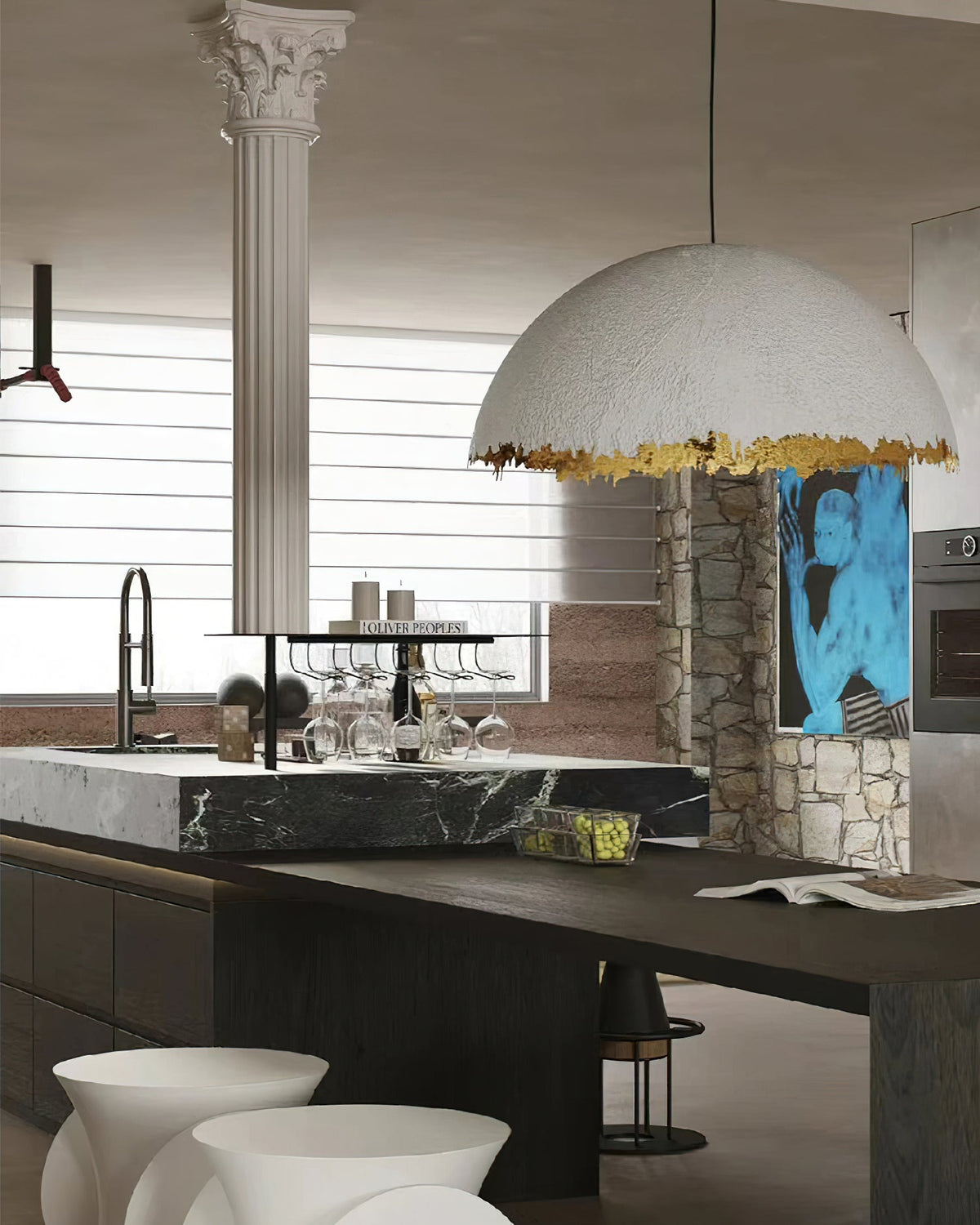 A broad Clérachic dome pendant with a jagged gold rim hangs over a stone-topped kitchen island with a dark counter.