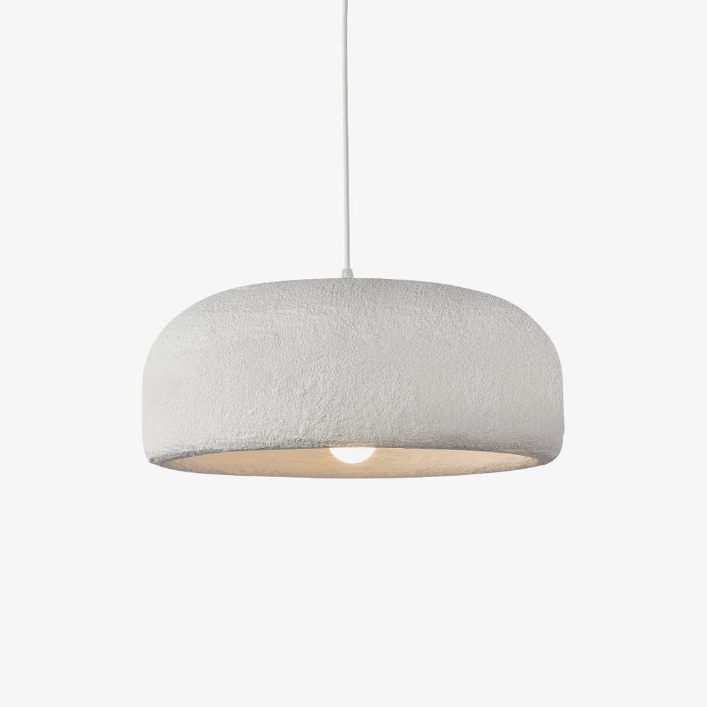 This Clérachic pendant on a plain light backdrop, a wide white dome shade with a rough plaster-like texture and a bare bulb glowing below.
