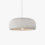 This Clérachic pendant on a plain light backdrop, a wide white dome shade with a rough plaster-like texture and a bare bulb glowing below.