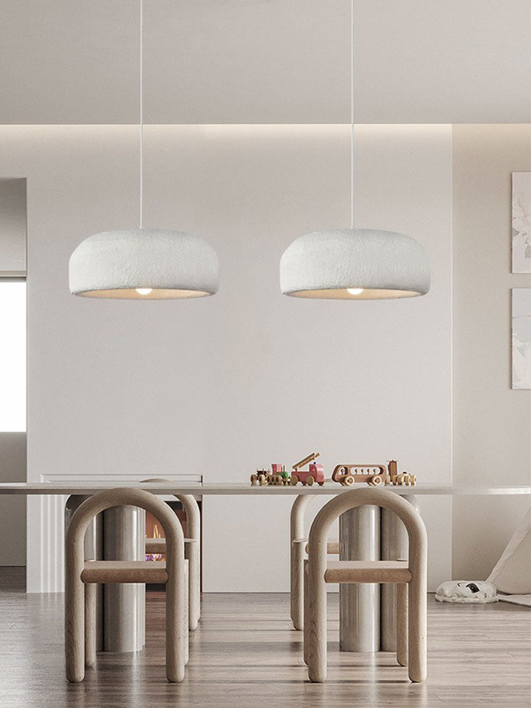 A pair of Clérachic dome pendants over a long table with arch-shaped wooden chairs, in a calm pale room.