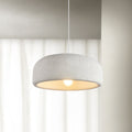 A Clérachic dome pendant hangs in front of sheer white curtains, its textured shade lit warm from the bulb below.