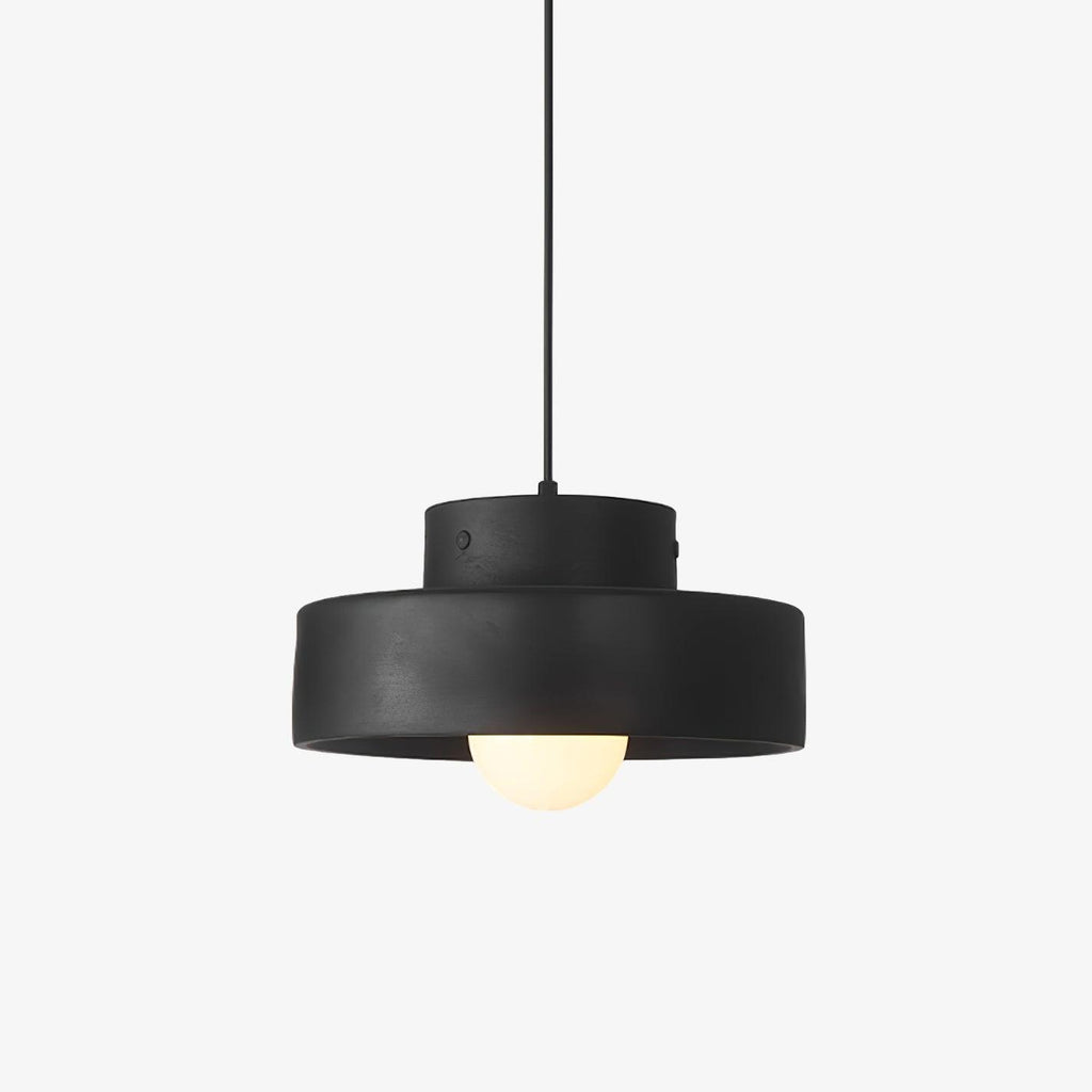 A black resin Clérachic pendant light with a stepped drum shade and a frosted globe bulb, on a plain white backdrop.