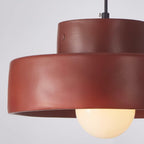 Close view of the red upper and lower drum of this Clérachic pendant, with the frosted bulb glowing beneath the rim.