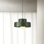 Green Clérachic pendant hanging in front of sheer white curtains, its frosted bulb glowing beneath the shade.