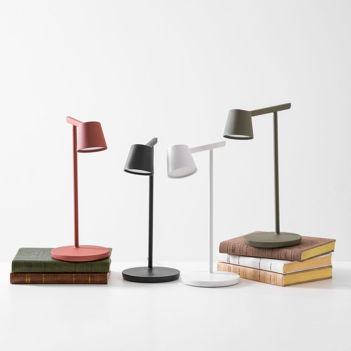 Four Clérachic table lamps arranged in a row on a white surface, with the heads aimed in different directions.