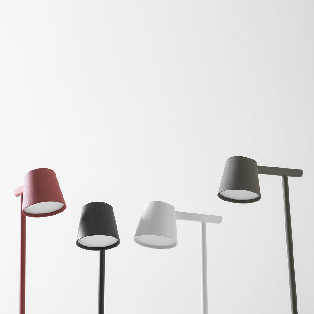 Close view of the lamp heads of four Clérachic table lamps in red, black, white and olive, lit from underneath.