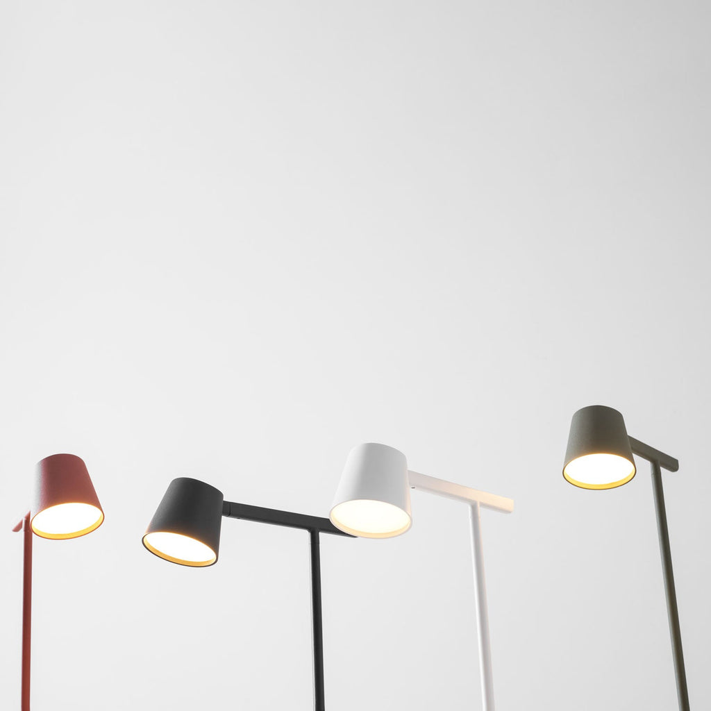 Low angle on four Clérachic table lamps in red, black, white and olive, with their heads lit against pale grey.