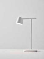 White Clérachic table lamp lit on a pale grey backdrop, with a soft pool of light on the surface beneath.