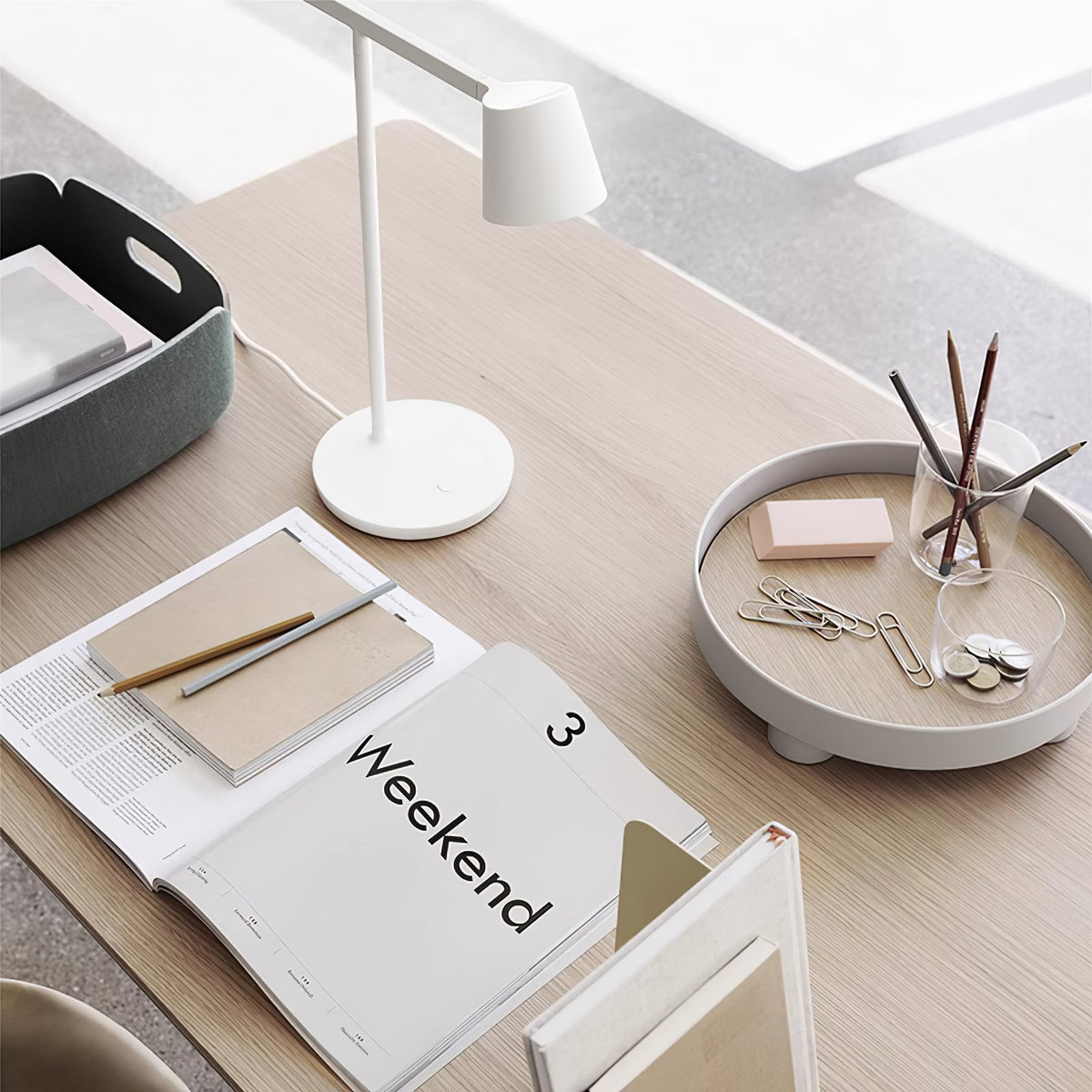 White Clérachic table lamp seen from above on a pale wood desk, with a tray, a pencil jar and an open magazine.