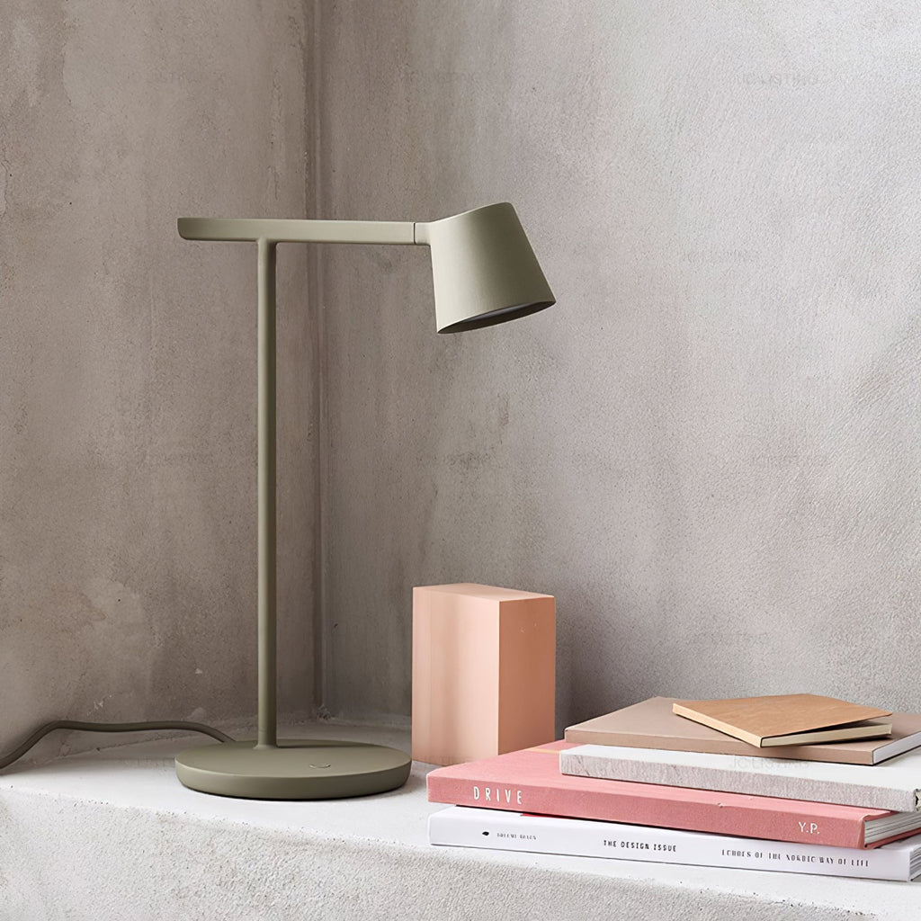 This Clérachic table lamp in olive on a concrete ledge, with a pink block and a few stacked books.