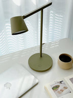 Olive Clérachic table lamp from above on a white desk, with a mug of coffee and a laptop in the corner.