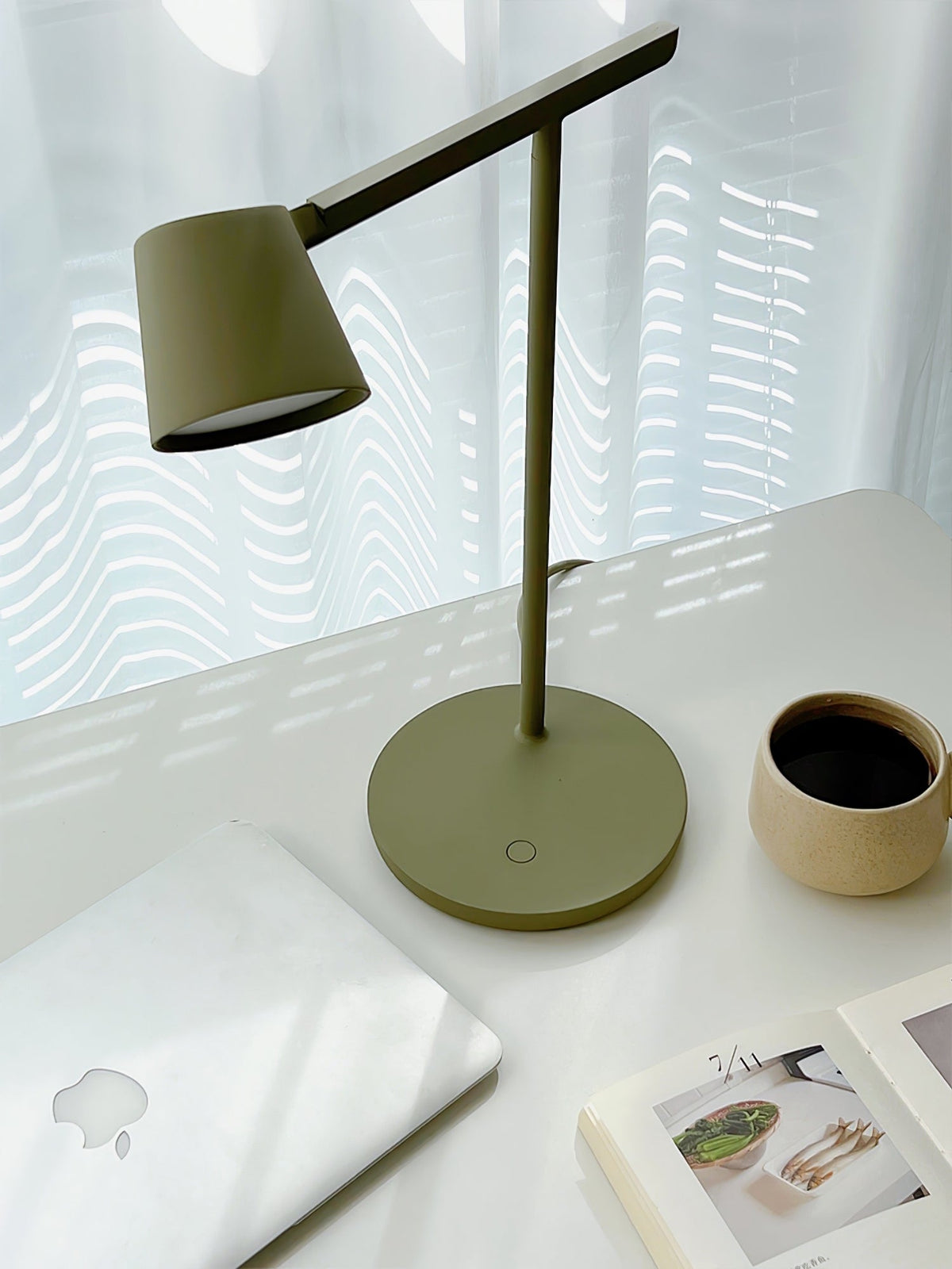Olive Clérachic table lamp from above on a white desk, with a mug of coffee and a laptop in the corner.