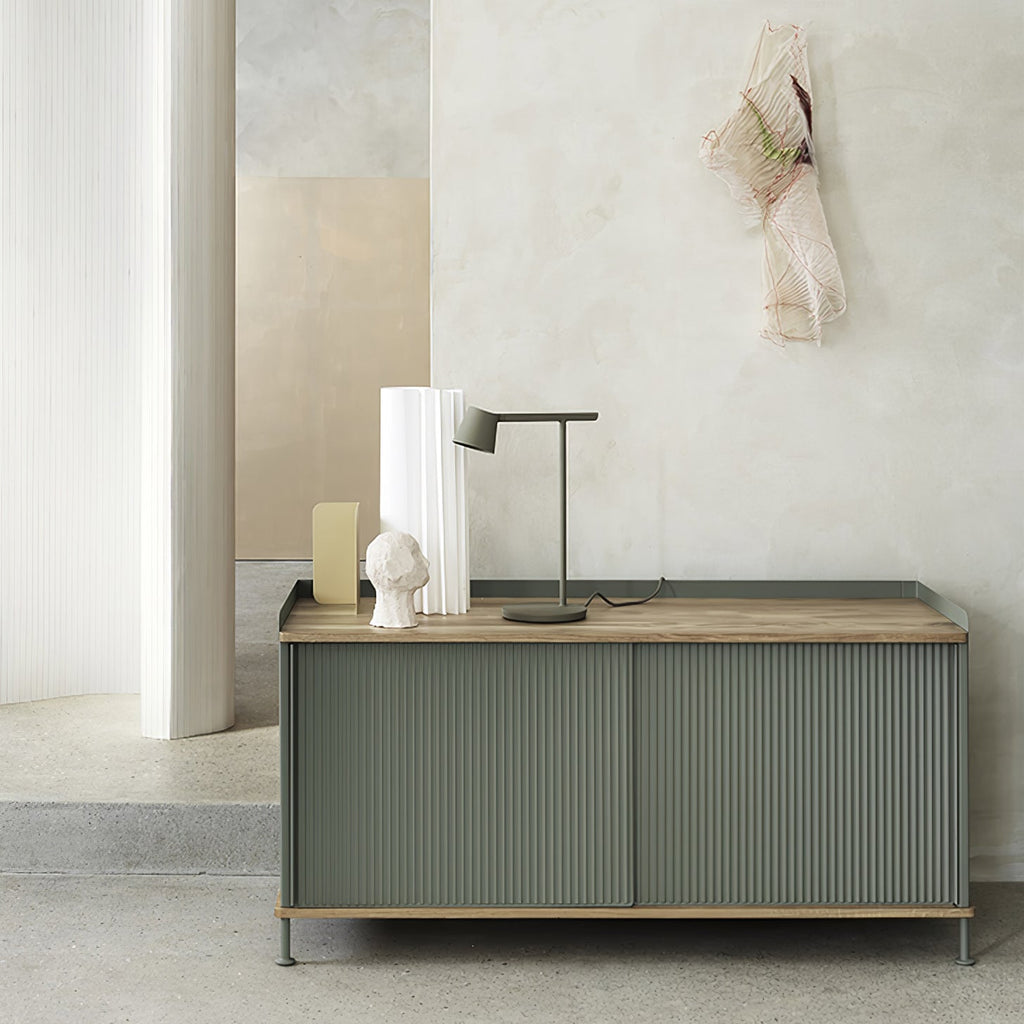 Olive Clérachic table lamp on top of a green sideboard, in a pale room with a white vase and a plaster head.