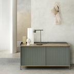 This Clérachic table lamp in olive on a sideboard with a wooden top, framed by a curved white wall.