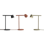 Black, rust-red and olive Clérachic table lamps in a row on white, the red lamp's head turned away.