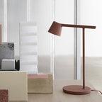 Rust-red Clérachic table lamp beside a tall white foam block and cream blocks, with a round disc base.