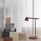 This Clérachic table lamp in rust-red, low in the frame, with a cluster of pastel blocks in front.