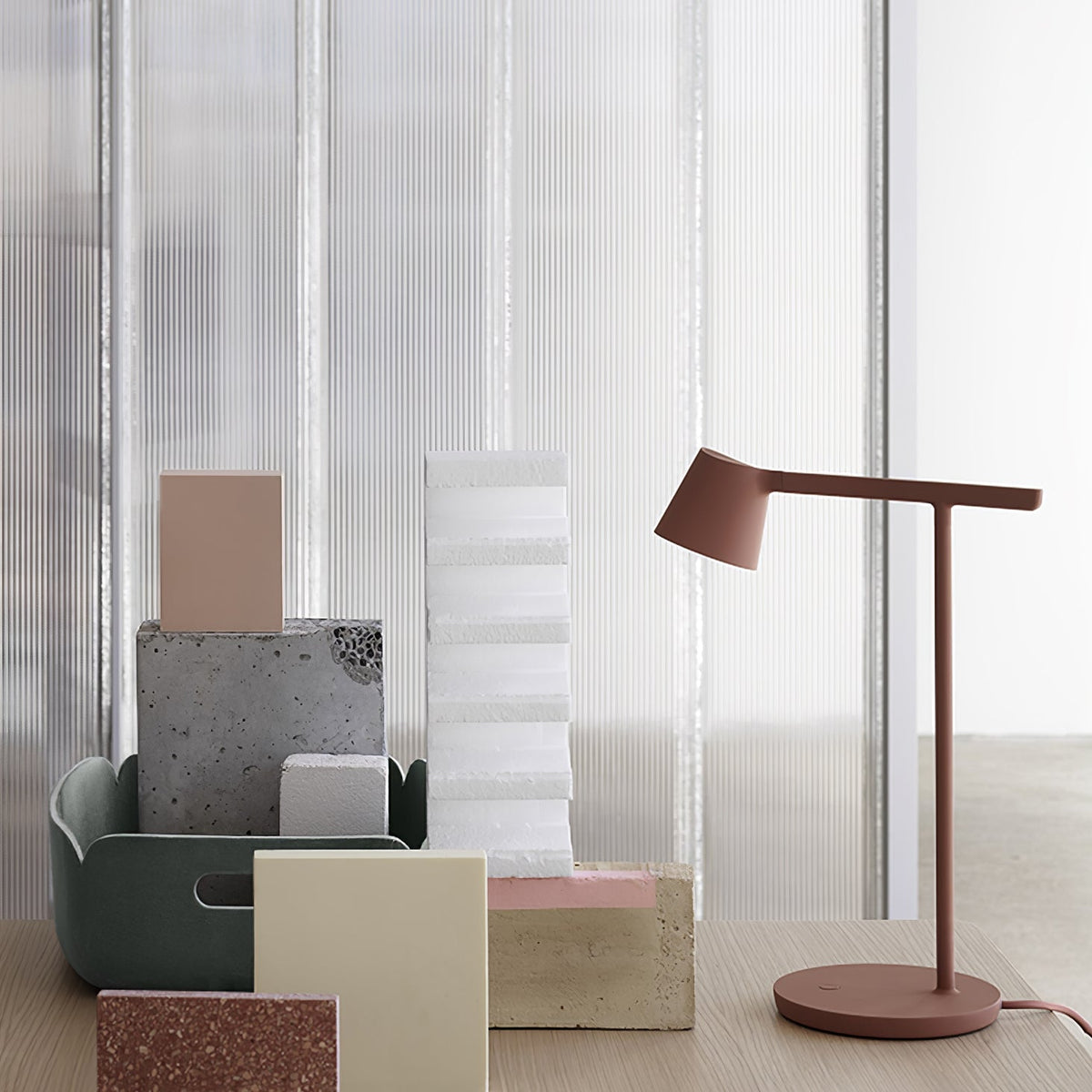 This Clérachic table lamp in rust-red, low in the frame, with a cluster of pastel blocks in front.