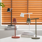 The four Clérachic table lamps at different heights, with orange wooden blinds behind and a stack of books under the white one.