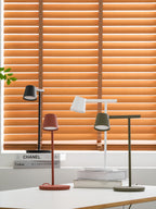 A wider view of four Clérachic table lamps grouped on a white desk, with the window frame and a leaf showing at the left.