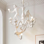 White Clérachic monkey chandelier hung from a ceiling rose in a pale room with decorative cornice moulding and a framed print.