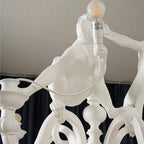 Close view of a resin monkey holding up a bulb and the turned baluster stem of this Clérachic chandelier.