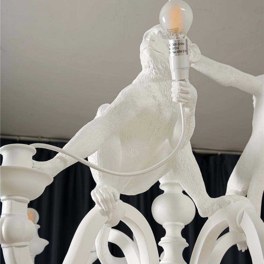 Close view of a resin monkey holding up a bulb and the turned baluster stem of this Clérachic chandelier.
