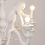 Close view of a resin monkey sitting on the stem and holding a bulb, beside a lit candle cup on this Clérachic chandelier.