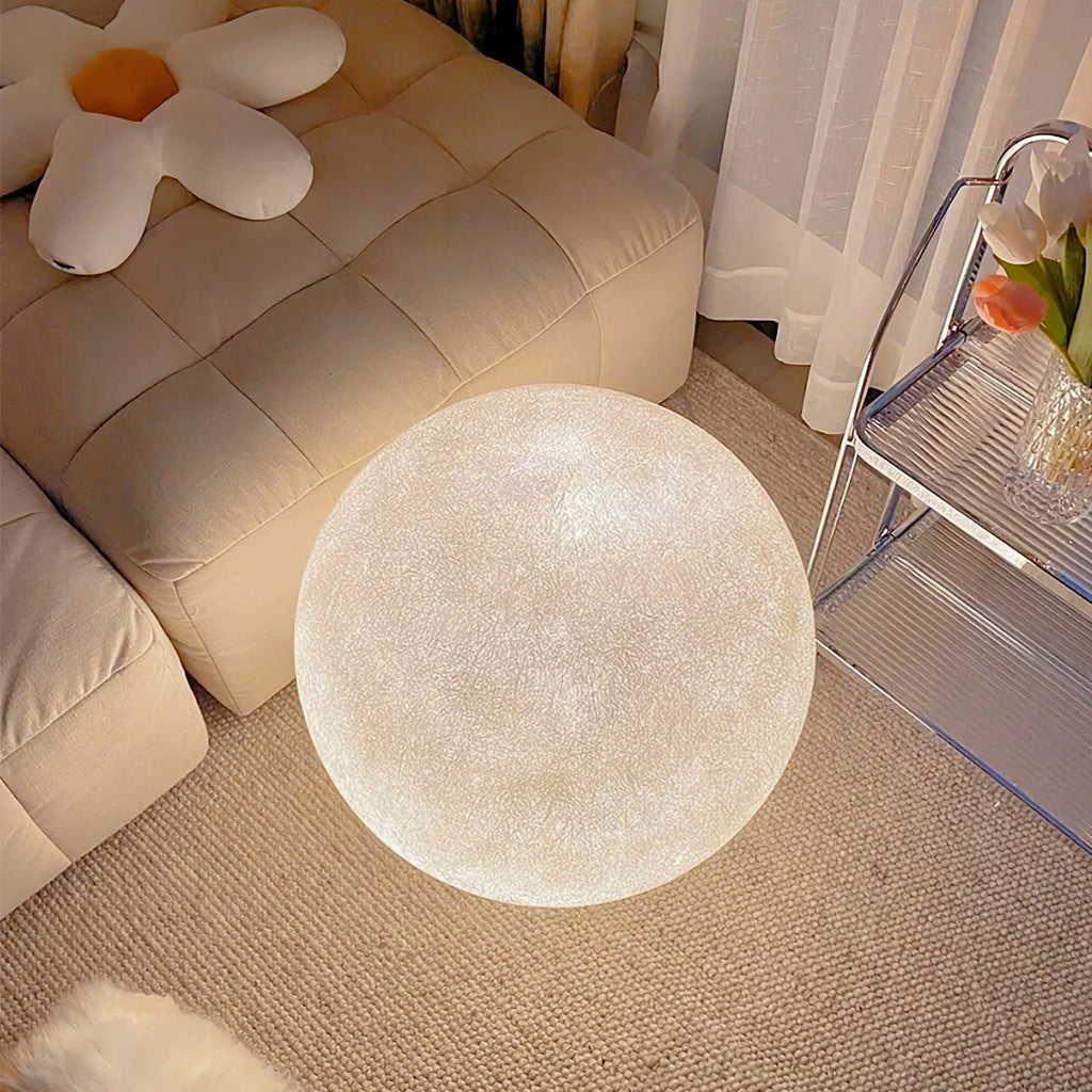 This Clérachic moon lamp rests on a beige carpet next to a quilted cream sofa and a clear acrylic trolley with tulips.