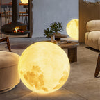 A lit Clérachic moon lamp with a golden, cratered surface sits near a fire and low wooden tables on a stone patio floor.