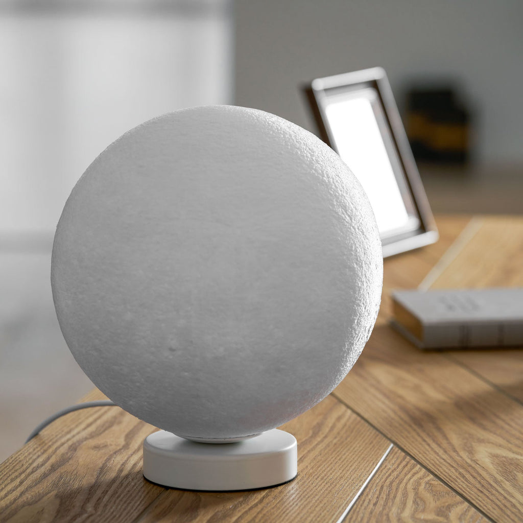 The largest unlit Clérachic moon table lamp shown close up, its cratered grey-white surface and round base filling the frame.