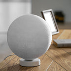 The largest unlit Clérachic moon table lamp shown close up, its cratered grey-white surface and round base filling the frame.