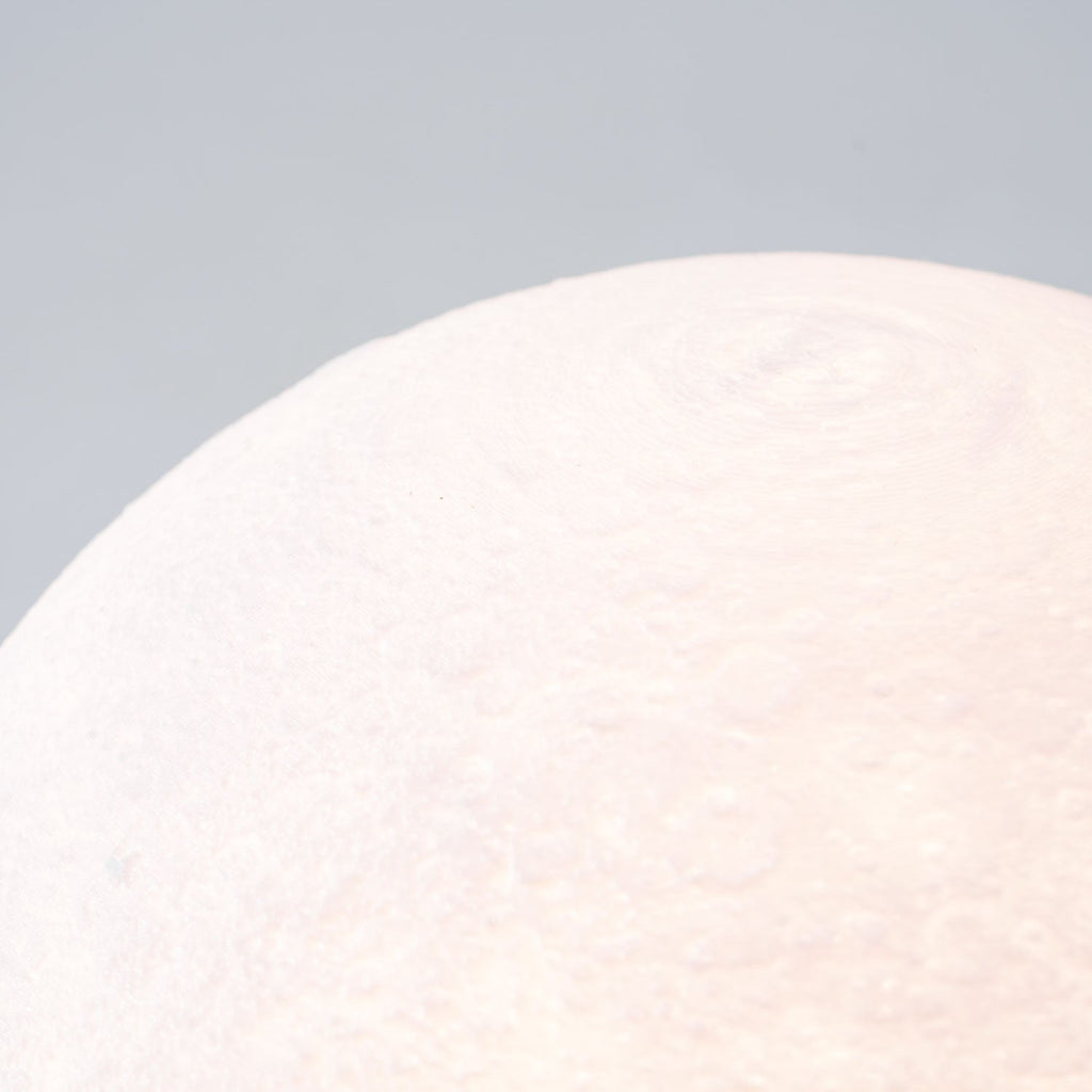 Close view of the fine cratered texture on the surface of this Clérachic moon table lamp, softly lit from within.