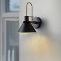 Clérachic Morandi horn-shade wall sconce in black, its brass arch catching daylight as it washes warm light down a pale wall.