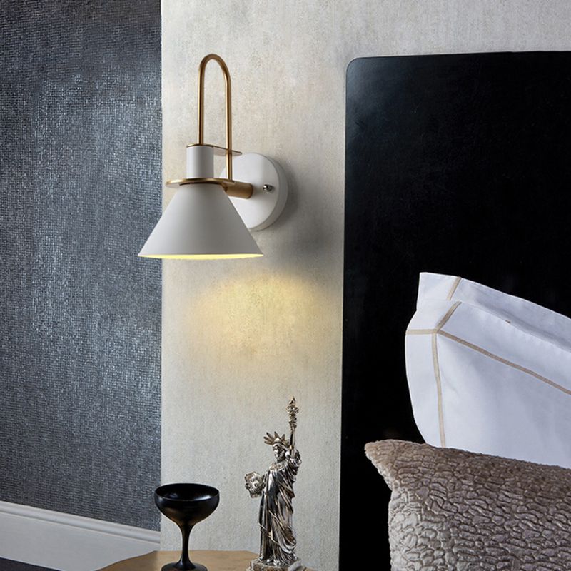The white Clérachic Morandi horn-shade wall sconce mounted beside a black headboard, throwing a soft cone of light down the bedside wall.