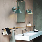 A pair of green Clérachic Morandi horn-shade wall sconces flanking a bathroom mirror above the vanity, where the IP44 rating lets them go.